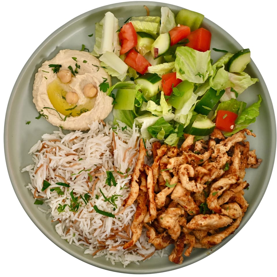 Mediterranean platter with grilled chicken, vermicelli rice, hummus, and a fresh lettuce, cucumber, and tomato salad.